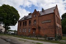 Dolsk. Za świątynią budynek dawnej szkoły sentencją na ścianie frontowej: <i>Ohne Fleiß kein Preis</i> (Bez pracy nie ma kołaczy).